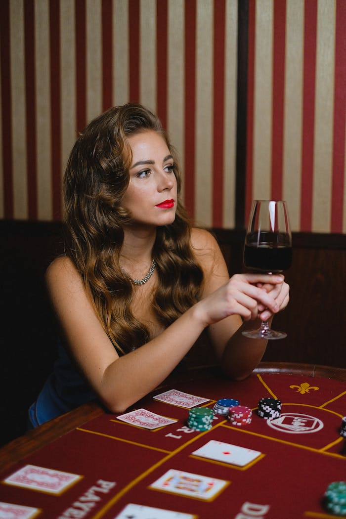 Stylish woman with wine glass at poker table, exuding elegance and concentration.