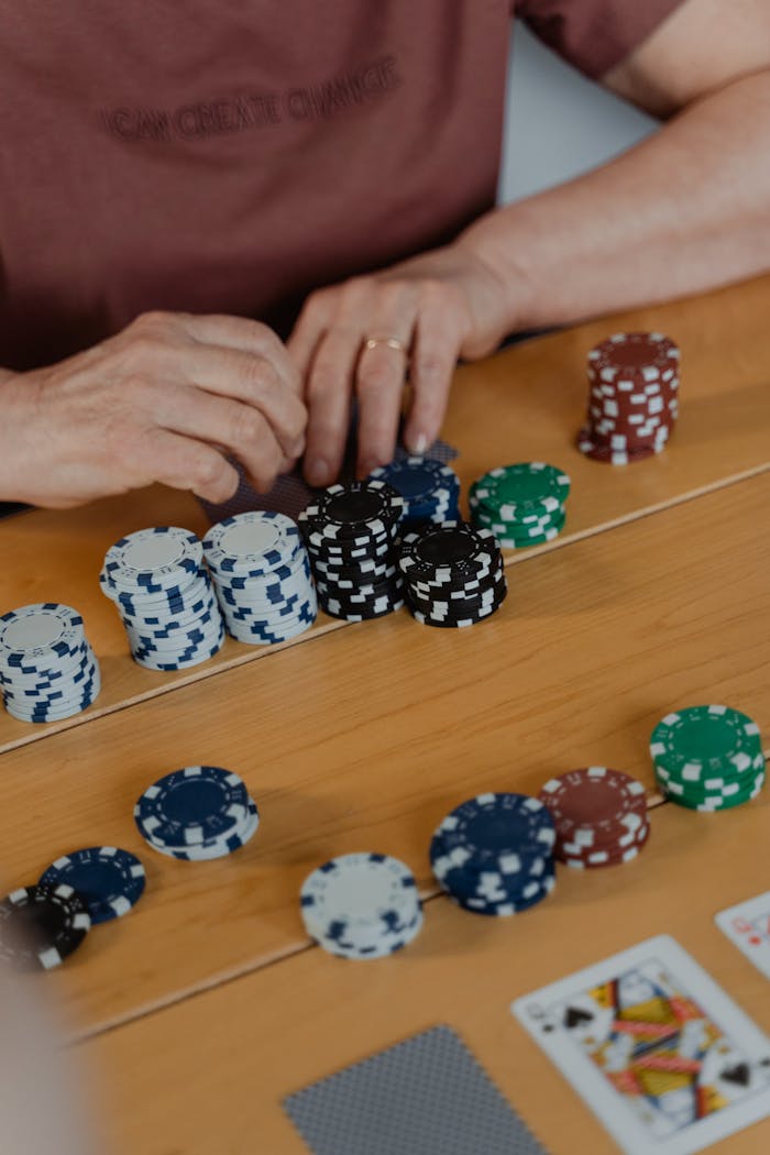 Close-up view of poker chips and player's hands during a game indoors.